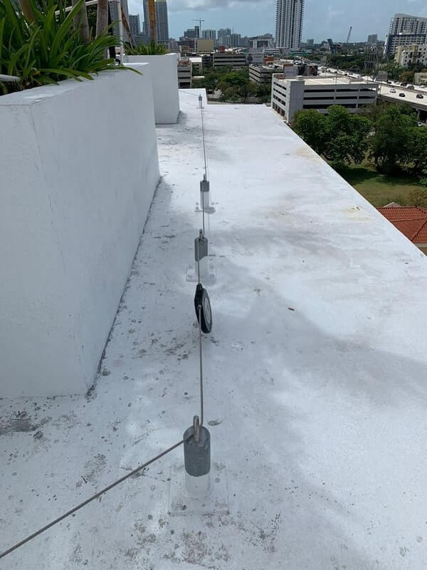Fall protection system wrapping around the roof edge of a concrete building