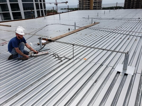 worker measuring safety of roof anchors
