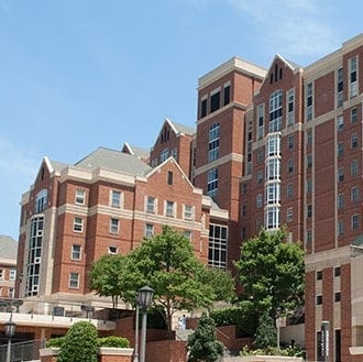 A multi-story brick building at the Georgia Institute of Technology in Atlanta, Georgia, featuring peaked roofs and equipped with a permanent roof anchor system. Lush greenery surrounds the structure.