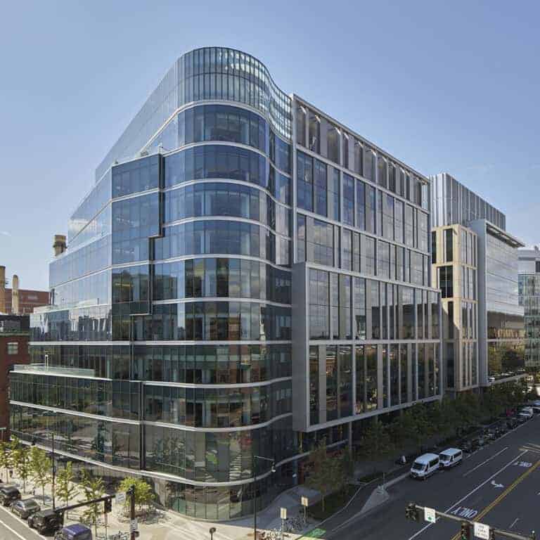 A sleek, modern office building with glass facades reflecting the urban landscape of Massachusetts.