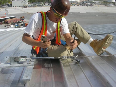 worker load testing a newly installed tieback anchor on a steel roof