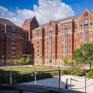 A multi-story brick building at the Georgia Institute of Technology in Atlanta, Georgia, featuring peaked roofs and equipped with a permanent roof anchor system. Lush greenery surrounds the structure.
